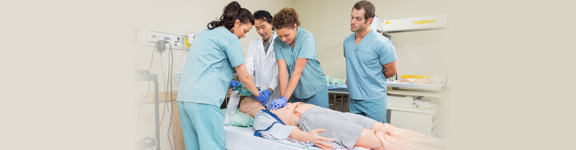 female nurse performing CRP on dummy patient while doctor and colleagues looking at her